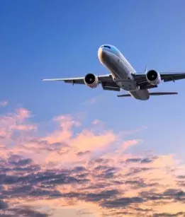 Plane in the air flying past clouds in a sunset