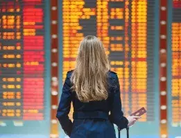 A woman standing in front of an airport flight status board