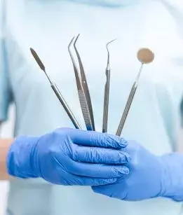 Dentist holding dental equipment in front of his body. 