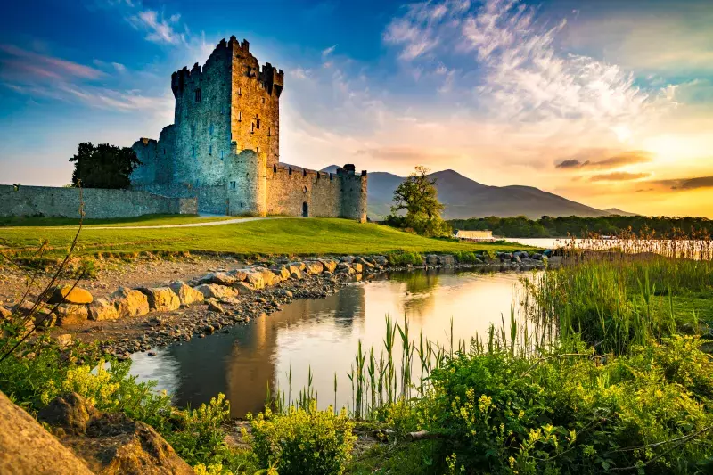 Ancient old Fortress Ross Castle ruin with lake and grass in Ireland during golden hour