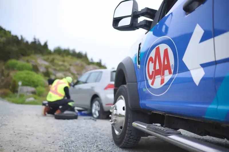 A CAA tech helps a member with a flat tire