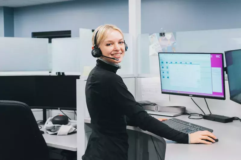 A woman smiling in front of a computer taking a roadside call