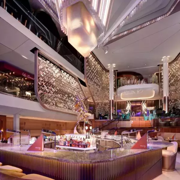 A luxurious cruise ship lounge with a stylish central bar, modern décor, sculptural accents, and elegant lighting.