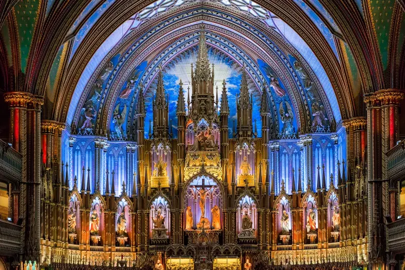 Ornate church interior with a grand altar, colorful lighting, and detailed gothic architecture.