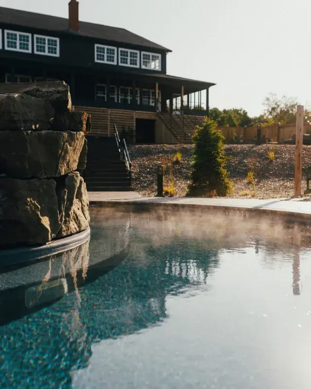 Steaming outdoor pool at a Nordic spa surrounded by stone and natural landscaping.