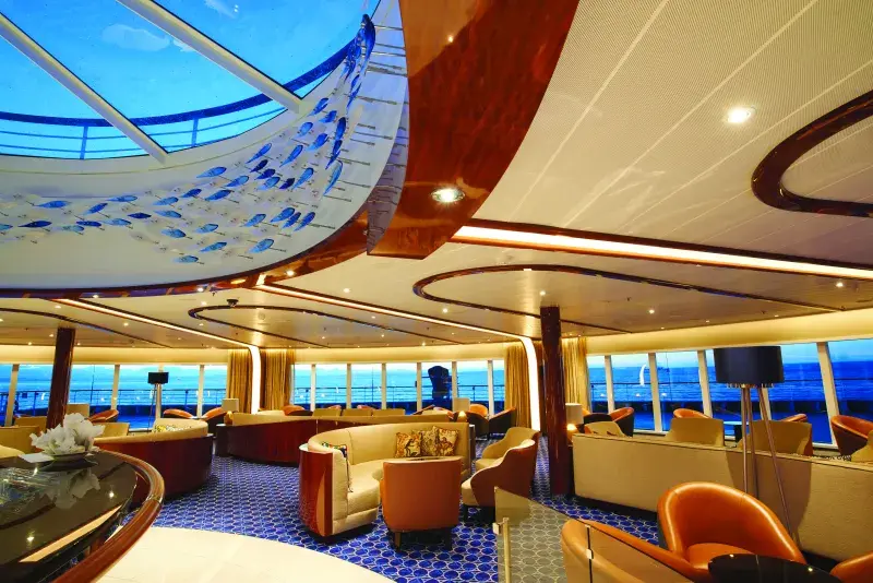 A lounging area on a Seabourn ship with a skylight and a view of the water from the windows