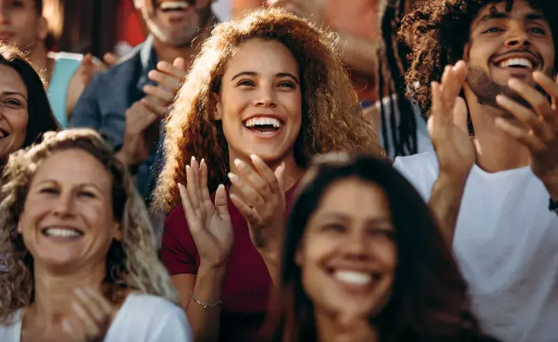 Audience members clapping during a live event.